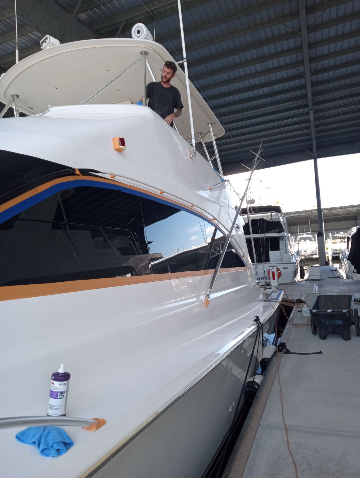 Sportfishing yacht hullside work at a covered dock